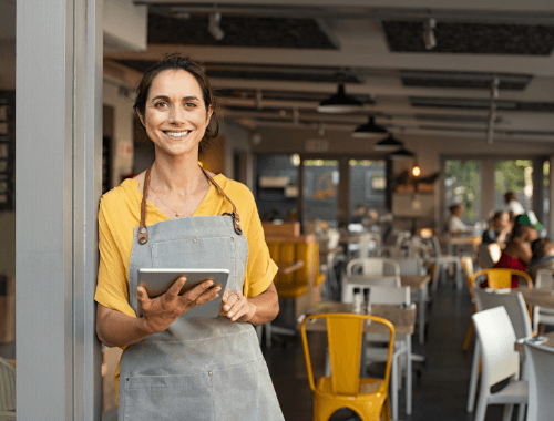 Woman with tablet stood in doorway of restaurant